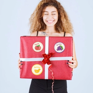 Dettaglio di adesivi colorati con frutta su confezione regalo con disegni di mela e uva