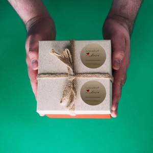 Close-up of circular kraft paper sticker with red heart and homemade with love text on a gift box