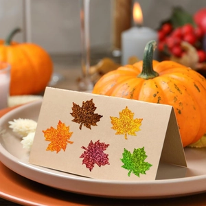 Glittery maple leaf stickers on beige card with pumpkin and candle autumn decor