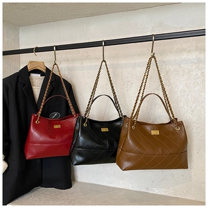 Close-up of quilted pattern tote bags with gold chain straps in red, black and brown