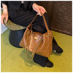 Detail shot of brown quilted leather tote bag with gold chain strap and turn-lock closure