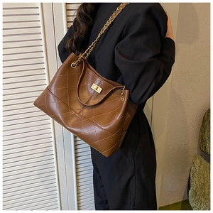 Detail of quilted brown tote bag with metallic twist lock and gold chain leather strap