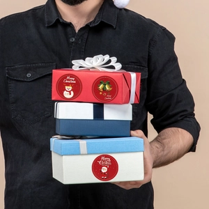 Macro view of Merry Christmas seal stickers on gift boxes with Santa and Snowman themes