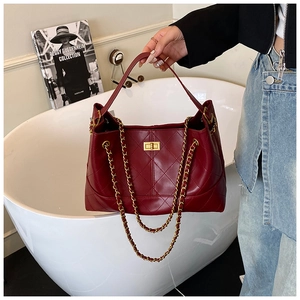 Detailed view of deep red quilted leather tote with gold turn-lock and chain straps