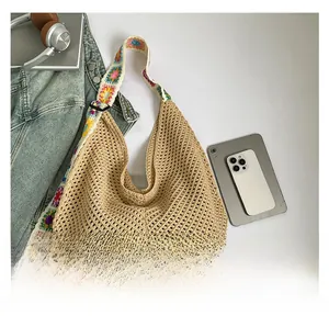Detail of hollow knit tote bag featuring colorful crochet floral shoulder strap and beige mesh