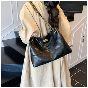 Close-up showing the quilted texture and golden chain strap of the black tote bag