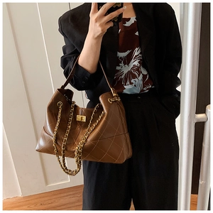 Detailed close-up of brown quilted leather bag featuring a gold chain strap and turn-lock