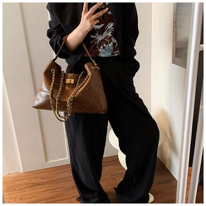 Detailed view of the dark brown quilted leather tote bag with gold chain and metal lock