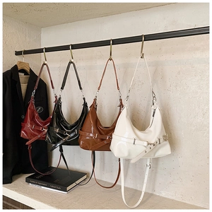 Détail du sac hobo en cuir verni brillant avec boucle décorative et bandoulière réglable