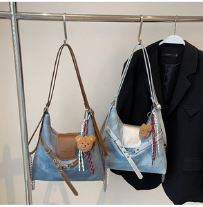 Detail view of denim texture crossbody bags with plush bear charms and chain straps
