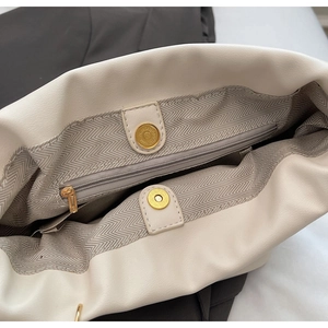 Detail of off-white PU bucket bag interior with gray herringbone lining and gold magnetic snap