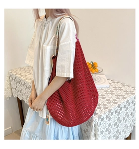 Detail of red crochet tote bag featuring intricate embroidery strap and knit texture