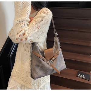 Detail of grey crossbody bag with brown leather flap and stylish metal chain strap