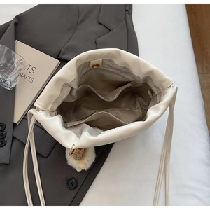 Interior view of white leather bucket bag with zipper pockets and plush ball charm