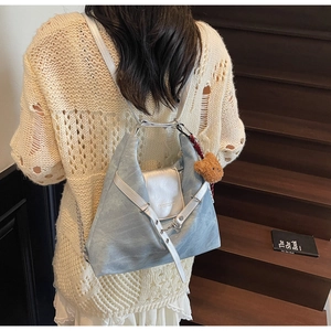 Detail of light blue and silver crossbody bag with a brown plush bear charm accessory