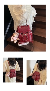 Detail eines bordeauxroten Lackleder-Rucksacks mit Silberkette und Plüschanhänger