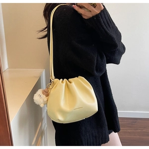 Detail of yellow pleated cloud bag with shoulder strap and cute plush lamb charm accessory