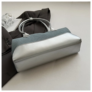 Detail of silver metallic and grey fabric patchwork bag with a metal ring handle