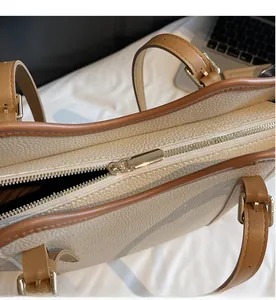 Vue détaillée de la fermeture éclair en métal doré et du cuir grainé sur le sac à main