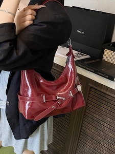 Sac fourre-tout minimaliste en cuir verni bordeaux avec boucle argentée porté par un mannequin