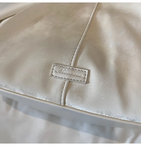 Detalle del bolso tote crema con tejido texturizado y parche con logo Nevermore