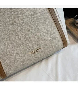 Détail du cabas en cuir grainé avec bordure marron et logo doré estampé sur le sac