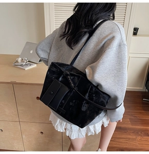 Detalle del bolso tote negro con textura arrugada y mini estuche en la correa de hombro