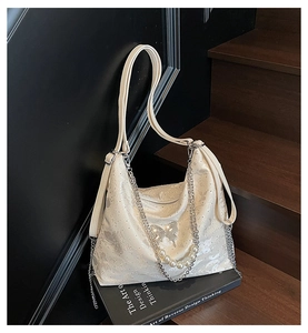 Detail of white pearlescent handbag with silver butterfly buckle and pearl chain