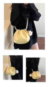 Detail of pale yellow drawstring bucket bag with soft leather texture and sheep charm