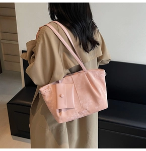 Bolso tote rosa de cuero sintético con textura fina y bolsillo frontal en una modelo
