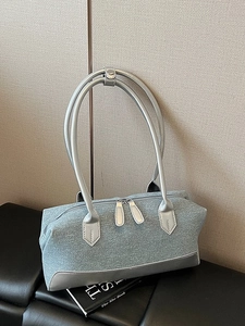 Denim fabric Boston bag with metallic silver trim and dual shoulder straps shown on a desk