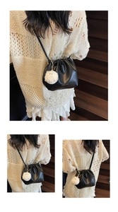 Detail of black drawstring crossbody bag with a cute monster plush charm on wood stairs