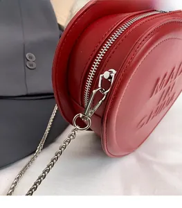 Detailed close-up of red heart leather bag showing silver zipper and metallic chain