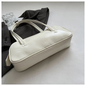 Close-up of minimalist white leather shoulder bag displayed on a grey suit background