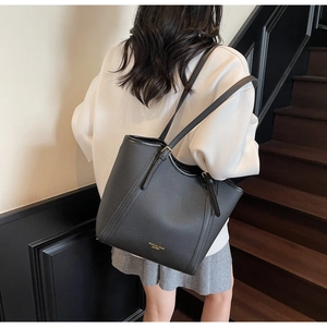 Gros plan du sac cabas en cuir noir avec texture litchi et lettrage doré à l'épaule
