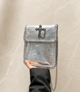 Detail of silver crocodile pattern square bag with gothic cross and chain edge