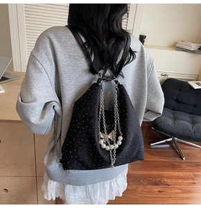 Detail of black denim tote bag with shimmering rhinestones and silver chain accents