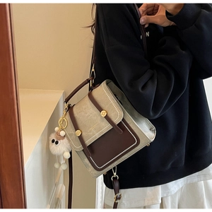 Detailed view of retro patchwork backpack with adjustable straps and plush charm on model
