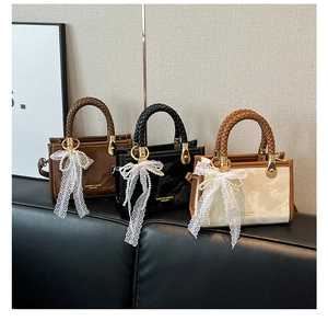 Detail of glossy patent leather handbags featuring woven handles and pearl lace charms