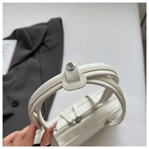 Detail of white leather handbag handle with silver round metal hardware and zipper