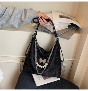 Detail of black denim tote with silver butterfly pendant and pearl chain decoration