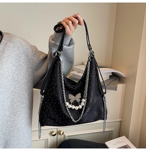 Close-up of black jacquard denim tote bag with silver butterfly and pearl chain detail