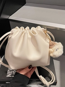 Off-white drawstring bucket bag with soft pleated texture and plush lamb charm