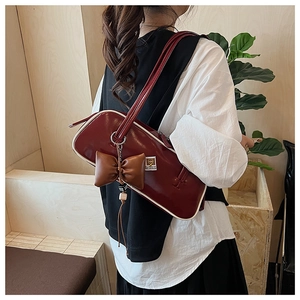 Detail of burgundy cylinder bag featuring glossy leather and white contrast piping
