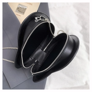 Macro view of heart-shaped crossbody bag interior with silver zipper and black lining