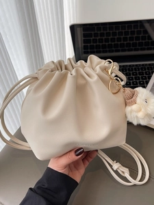 Chic drawstring bucket bag in cream PU leather with soft pleats and cute plush charm