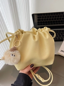 Minimalist creamy yellow drawstring bucket bag with cute plush pendant for women