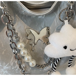 Dettaglio della borsa argento metallizzato con farfalla fluida e catena di perle