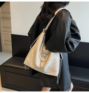 Detail of cream white shoulder bag with butterfly print, silver chain, and pearl accents