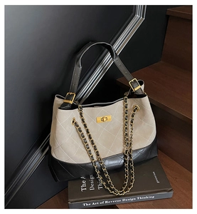 Detail of beige suede and black leather shoulder bag with golden chain and lock